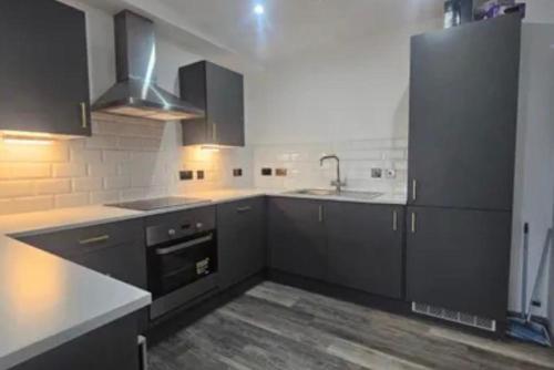 a kitchen with black cabinets and white counter tops at 1 Bedroom Luxury Apartment Winkley Square in Preston