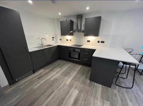 a kitchen with black cabinets and a white counter top at 1 Bedroom Luxury Apartment Winkley Square in Preston