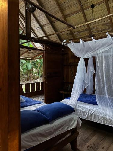 two beds in a room with a canopy at Ecolodge Azul Paradise in Nuquí