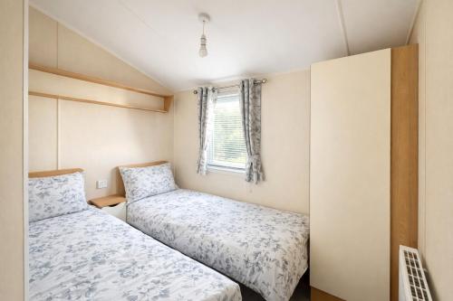 two beds in a small room with a window at Cozy Family Caravan at Haven Kent Coast in Allhallows
