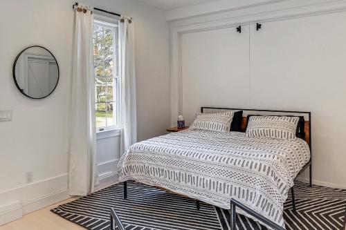 a bedroom with a bed with a mirror and a window at Steps to NYC Train! Charming Carriage House Loft in Glen Ridge