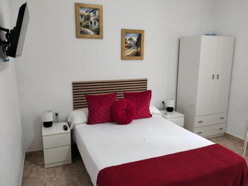 a bedroom with a large white bed with red pillows at El Rinconcito de Ensueño in Gran Tarajal