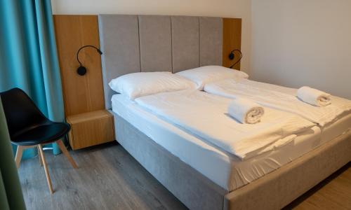 a bed with two pillows and a chair in a room at Liptov Hills in Liptovský Mikuláš