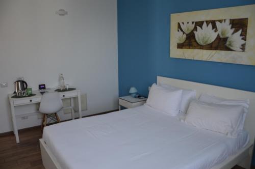 a bedroom with a white bed with a blue wall at BLUE Airuno in Airuno