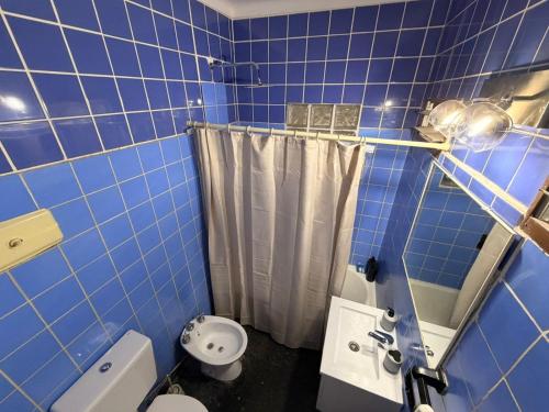 a blue tiled bathroom with a toilet and a shower at Casa Morotï - Casa de dos habitaciones en la Costanera de Corrientes in Corrientes