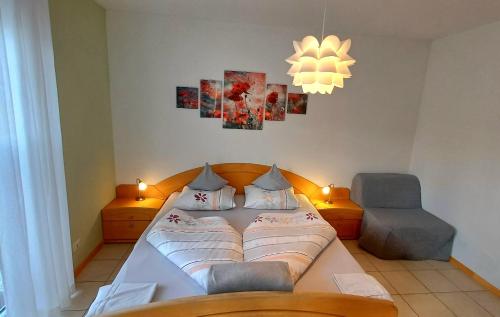 a bedroom with a bed and a chair and a chandelier at Fischerhof Agriturismo in Cornaiano