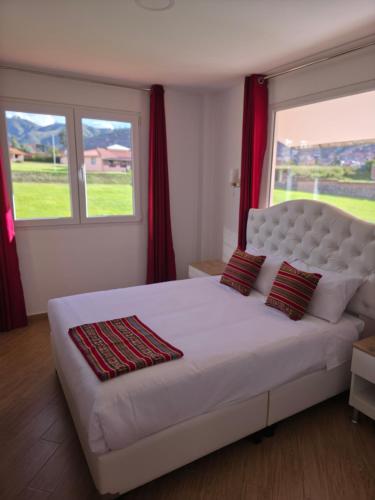 a bedroom with a large white bed with red curtains at Villa Arcadia Hotel & Eventos Cusco in Cusco