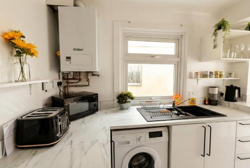 a kitchen with a washer and a sink and a stove at Central Gosport Group Townhouse with Dedicated Workspace, Sleeps 9 in Brockhurst