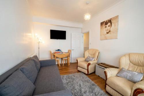 a living room with a couch and chairs and a tv at Central Gosport Group Townhouse with Dedicated Workspace, Sleeps 9 in Brockhurst