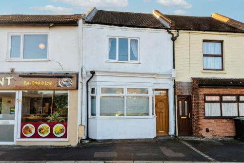 a white building with a store front at Central Gosport Group Townhouse with Dedicated Workspace, Sleeps 9 in Brockhurst