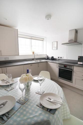 a kitchen with a table with plates and flowers on it at Franks- 2nd Floor Apt-2 Bath-Cowes Centre-Sleeps 4 in Cowes