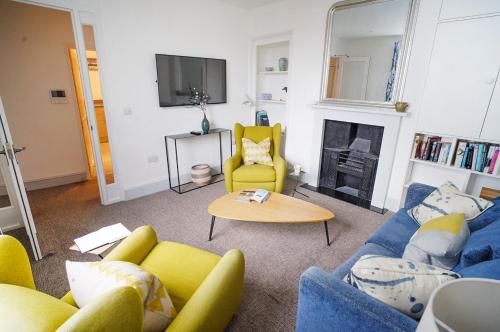 a living room with a blue couch and yellow chairs at Paskins - Cowes in Cowes