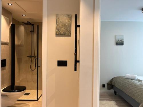 a bathroom with a shower and a toilet and a bed at Affordable Luxury Apt - Hotel Vibe - Heart of Voss in Vossevangen