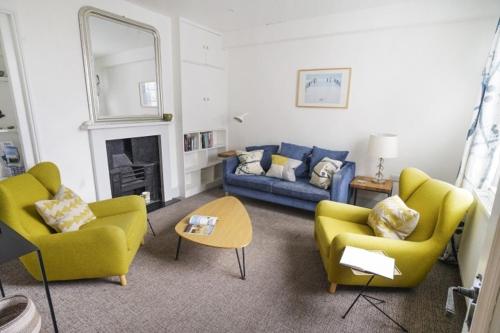 a living room with yellow chairs and a blue couch at Paskins - Cowes in Cowes