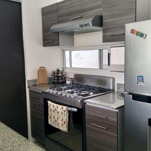 a kitchen with a stove top oven next to a refrigerator at Liverté Armonia 102 in Cancún