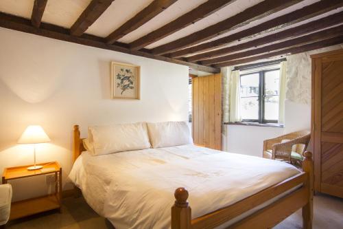 a bedroom with a white bed with a wooden ceiling at The Long Barn nr Huntsham in Tiverton