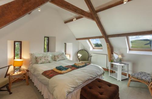 a bedroom with a bed in a room with windows at Putham Barn Cutcombe in Wheddon Cross