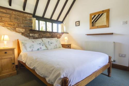 a bedroom with a bed in a room with a stone wall at May Cottage nr Huntsham in Tiverton