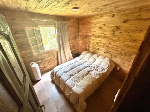 a bed in a wooden room with a window at Increíble cabaña de montaña in Potrerillos