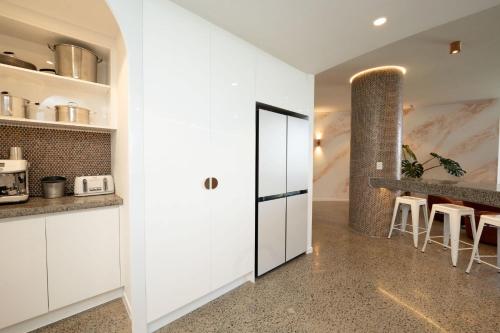 a kitchen with white cabinets and a counter with stools at 19th Avenue on the Beach in Gold Coast