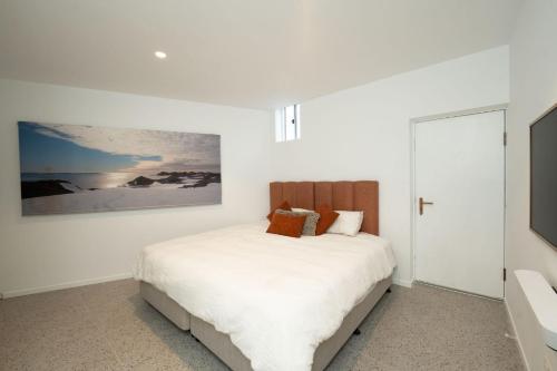 a white bedroom with a bed and a tv at 19th Avenue on the Beach in Gold Coast