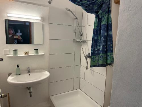 a woman taking a picture of a bathroom with a sink and shower at Ferienwohnung Relax 1 in Hahnenklee-Bockswiese