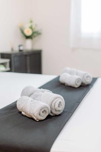 two rolled towels sitting on a black blanket on a bed at The Calm City Escape in Heraklio