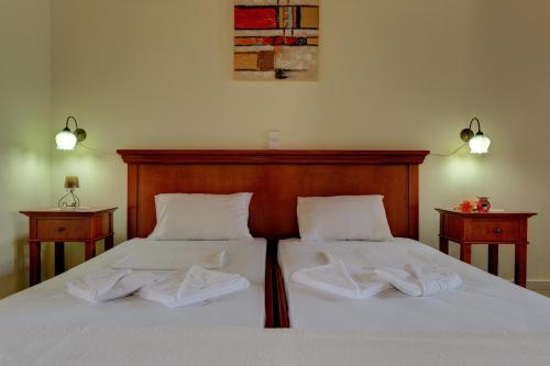 a bedroom with two beds with white sheets and towels at Iliopetra in Douliana