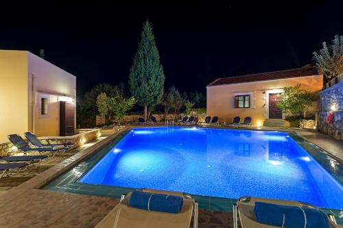 a large blue swimming pool in a yard at night at Iliopetra in Douliana