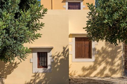 two images of a building with a door and a tree at Iliopetra in Douliana