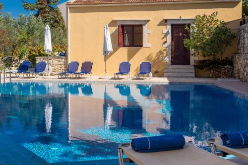 a pool with chairs and umbrellas next to a building at Iliopetra in Douliana