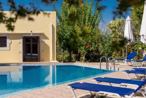 a swimming pool with chairs and a house at Iliopetra in Douliana