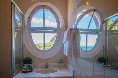 baño con 2 ventanas circulares y lavamanos en Villa Ricardo, en Porto da Cruz