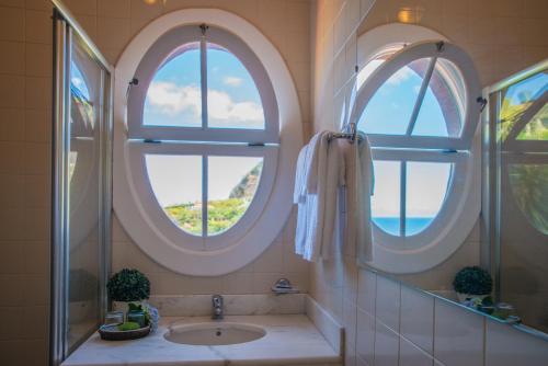 ポルト・ダ・クルースにあるVilla Ricardoの円形の窓2つとシンク付きのバスルーム