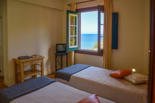 ポルト・ダ・クルースにあるVilla Ricardoのベッドルーム1室(ベッド2台付)、海の景色を望む窓が備わります。