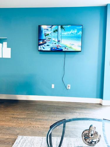 a tv hanging on a blue wall in a living room at Temperly Heavon in Newark