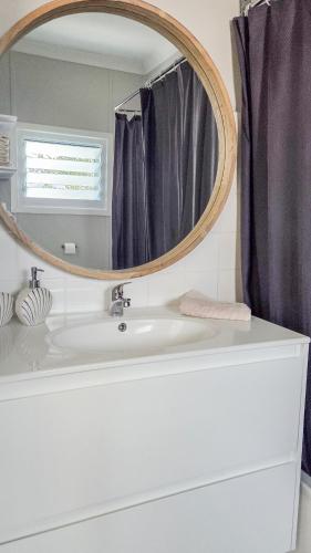 a bathroom with a round mirror over a sink at Harrington Holiday House in Harrington