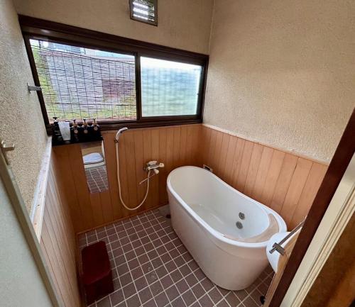 a small bathroom with a tub and a window at Kominka engawa in Kakamigahara