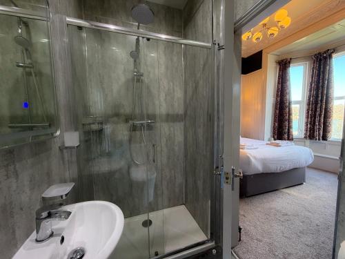 ein Badezimmer mit Dusche, Waschbecken und Bett in der Unterkunft Nomi Rooms & Restaurant in Bangor