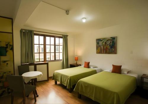 a room with two beds and a table and a window at Casa de Baraybar in Lima