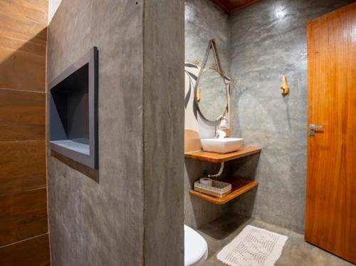a bathroom with a toilet and a tv and a mirror at Chalé Lar do Capão in Vale do Capao