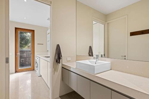 a white bathroom with a sink and a mirror at Kingsley in Point Lonsdale