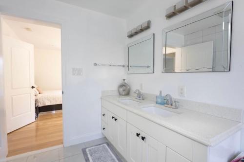 a white bathroom with a sink and a mirror at Charming Home for a Perfect Escape in East Hampton