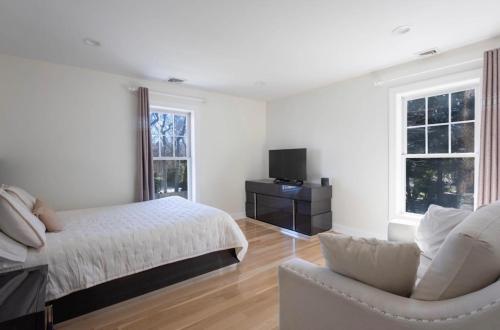 a white bedroom with a bed and a chair at Charming Home for a Perfect Escape in East Hampton