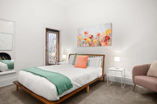 a white bedroom with a bed and a chair at Albertine House in Melbourne