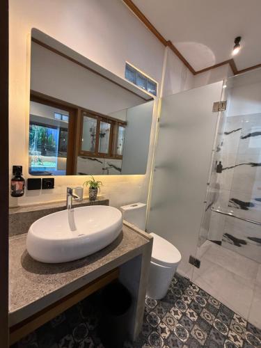 a bathroom with a sink and a toilet and a mirror at Koji Collection in Kerobokan