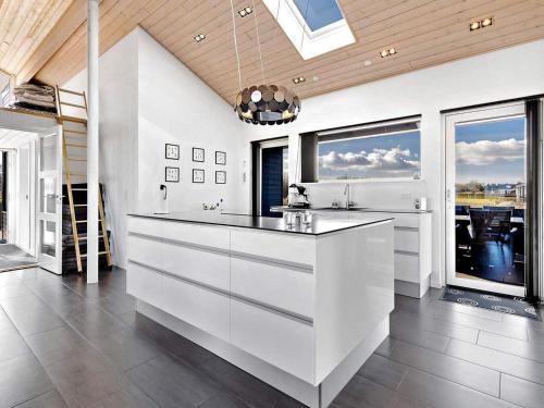 a kitchen with white cabinets and large windows at Coastal Home with Spa and Sauna in Spodsbjerg