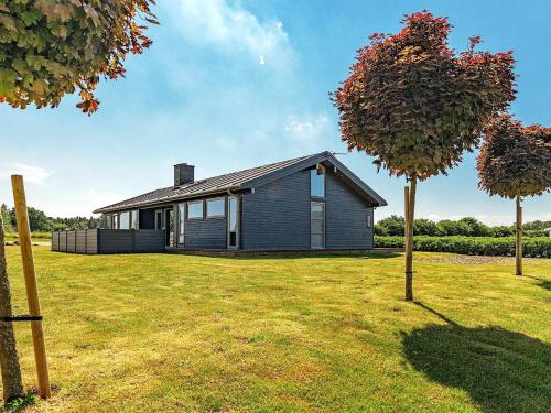 a small house in a yard with a tree at Coastal Home with Spa and Sauna in Spodsbjerg