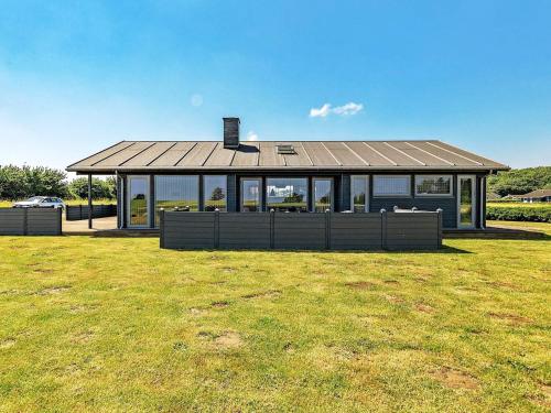 a large house with a roof on a grass field at Coastal Home with Spa and Sauna in Spodsbjerg