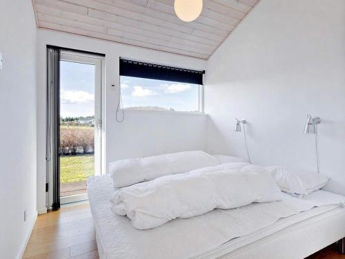 a white bedroom with a large bed with a window at Coastal Home with Spa and Sauna in Spodsbjerg